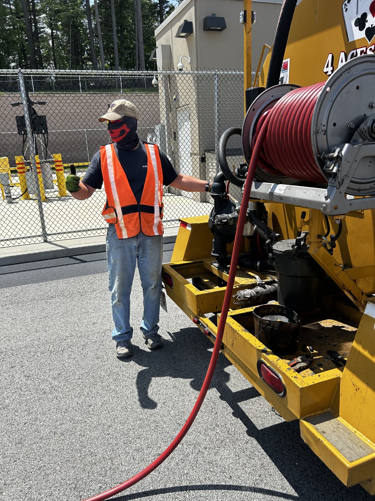 AAA Supercoat crew member next to branded sealcoating equipment truck